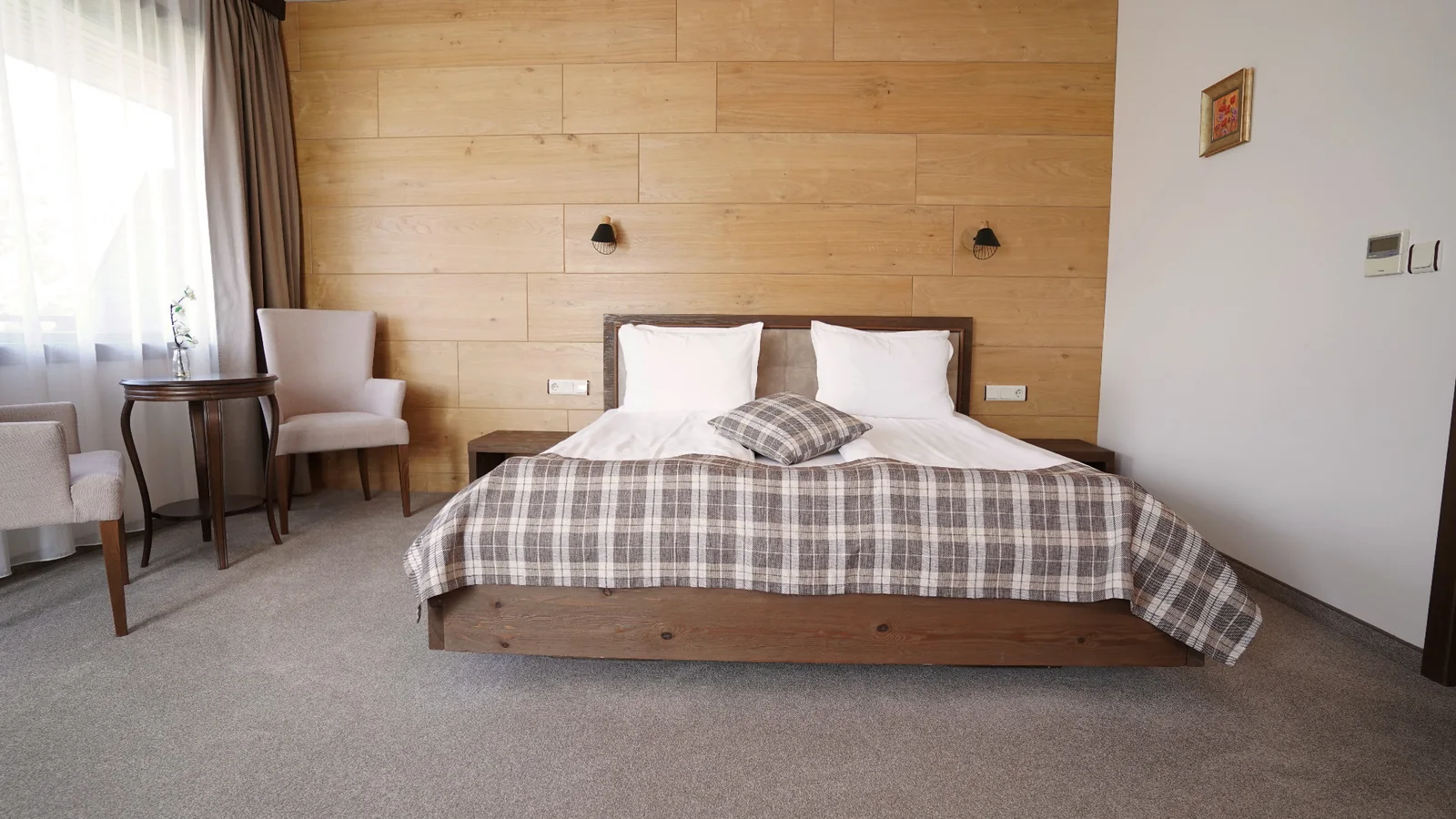 Double bed with a wooden wall and bedside lamps